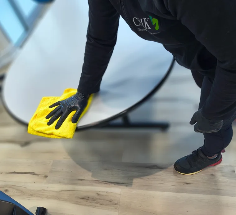 CSIK Cleaning technician wearing black gloves providing deep cleaning services by wiping down an office table.