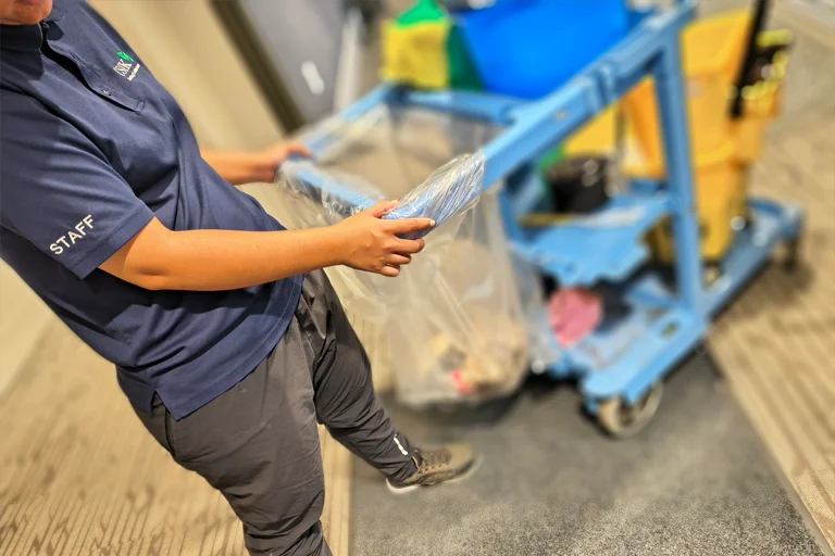 CSIK cleaner pushing a janitorial cart down an office hallway