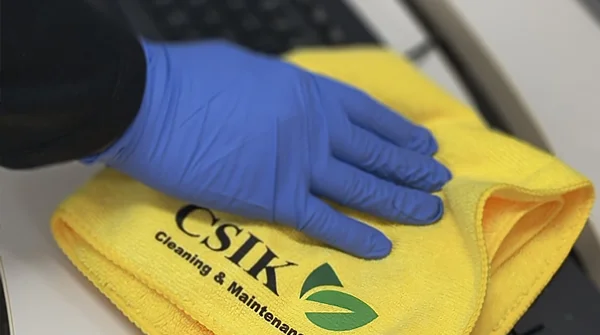 CSIK cleaner sanitizing an office desk and keyboard with a microfiber cloth