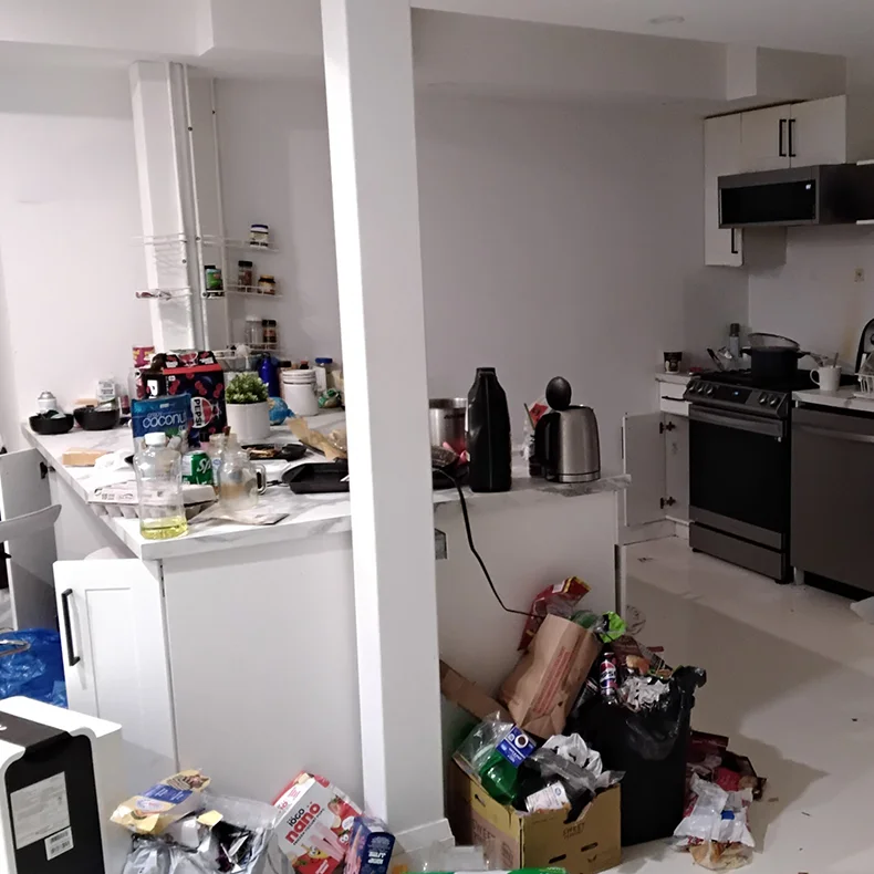 A interior view of an unorganized kitchen space filled with food containers, cluttered countertops, and overflow trash piles prior to professional deep cleaning and organization services by CSIK.